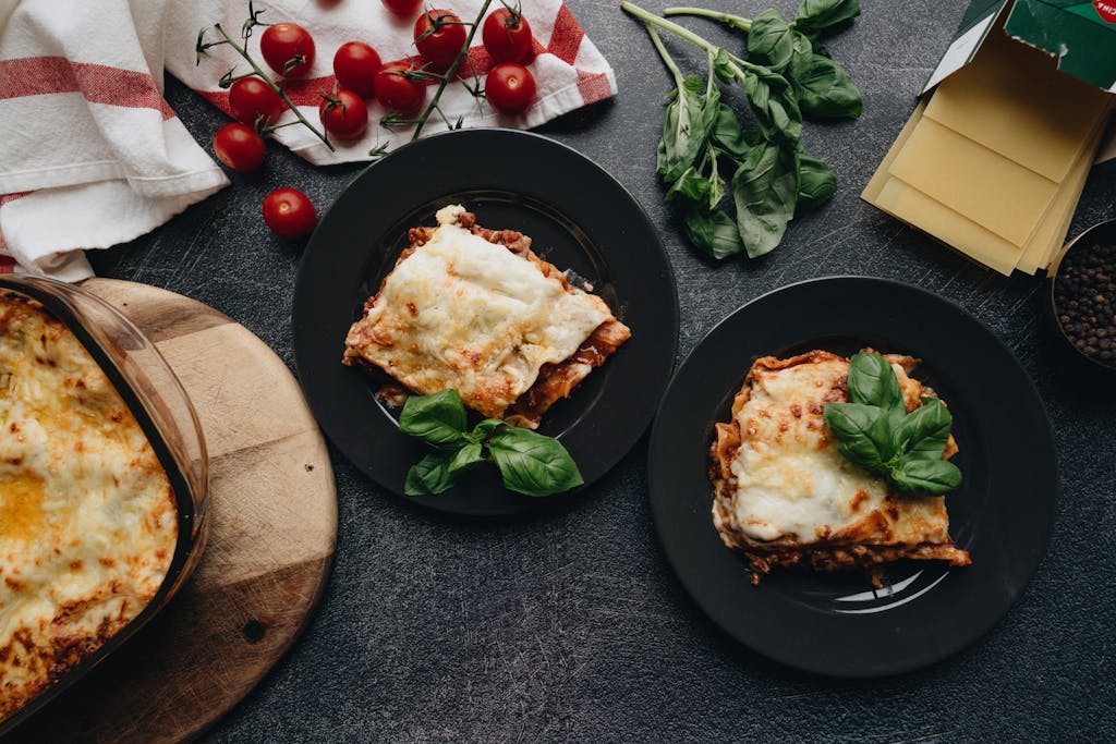Delicious homemade lasagna served with fresh tomatoes and basil, perfect for Italian cuisine lovers.